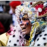 Person in colorful carnival costume with clock headpiece.