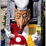 Giant puppet in parade with colorful costume.
