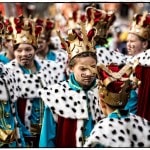 Group in royal costumes with crowns at festival.