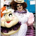 Person in elaborate costume holding teapot prop.
