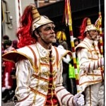 Carnival performers in colorful costumes and red plumes