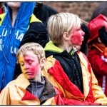 Children with painted faces wear colorful jackets.