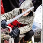 Child dressed as knight with toy sword.