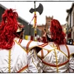 Festival parade with red-haired costumes.