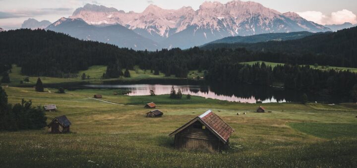 Brown Wooden House on Green Grass Field Near Green Trees and Mountains