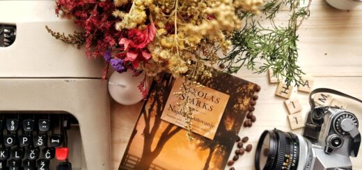 Bunch of flowers and book arranged on wooden table with vintage typewriter and camera