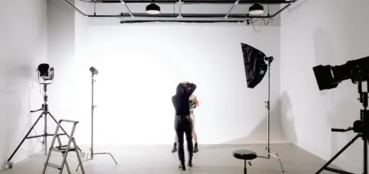 Back view of unrecognizable professional photographer taking photo of anonymous model in modern light studio